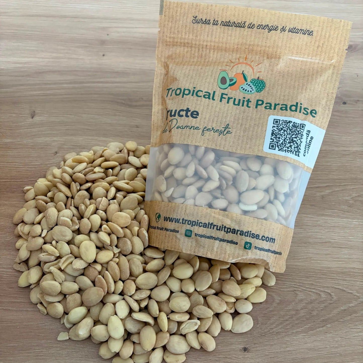 Premium peeled Belona almonds with a round, flat shape and light cream color, spilling out from a small kraft pouch onto a wooden table.