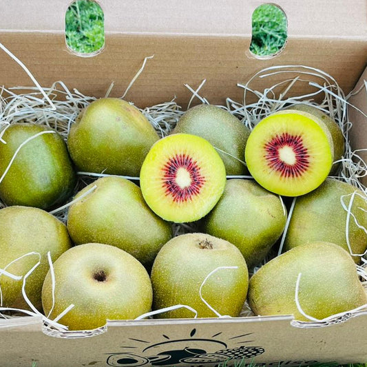 Box of kiwis with one sliced open on a grassy background