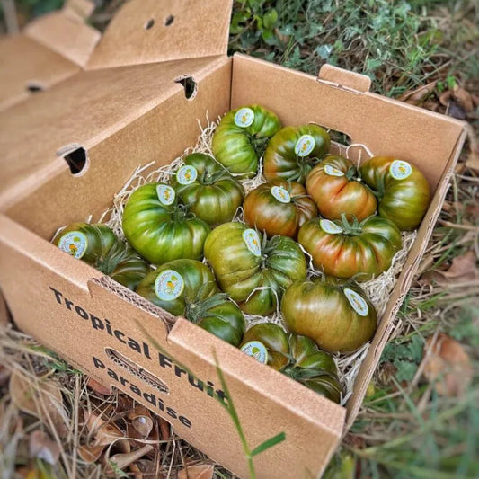 Box of green tomatoes with labels on a natural background