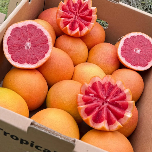 4 kg box of premium red grapefruit, featuring decorative star-shaped cuts to reveal the juicy texture, in a cardboard delivery box on green grass.