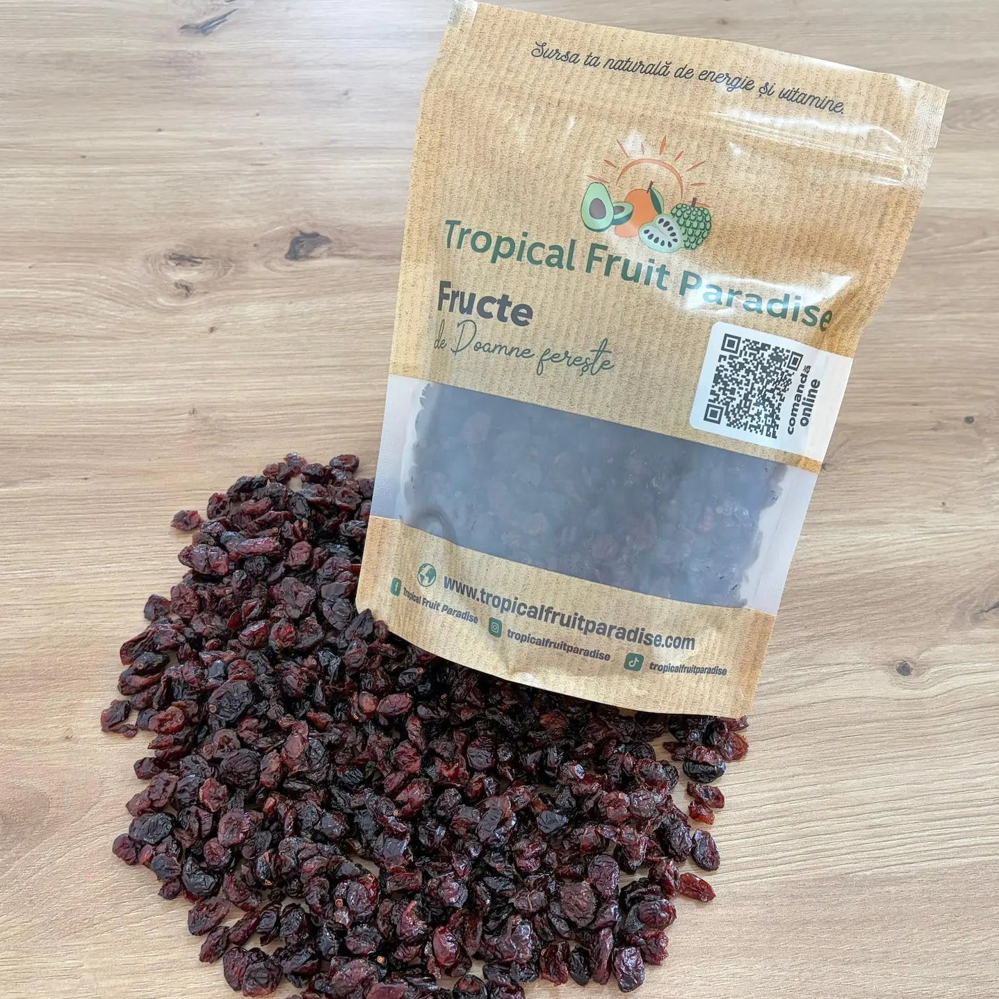 Dried cranberries spilled from a branded Tropical Fruit Paradise kraft pouch with a QR code, displayed on a light wooden background.