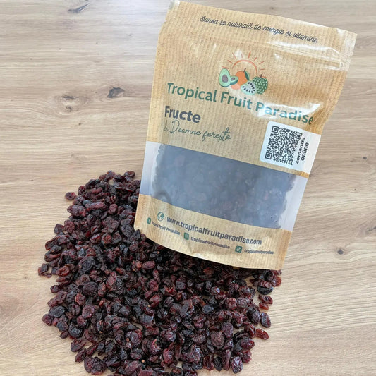 Dried cranberries spilled from a branded Tropical Fruit Paradise kraft pouch with a QR code, displayed on a light wooden background.