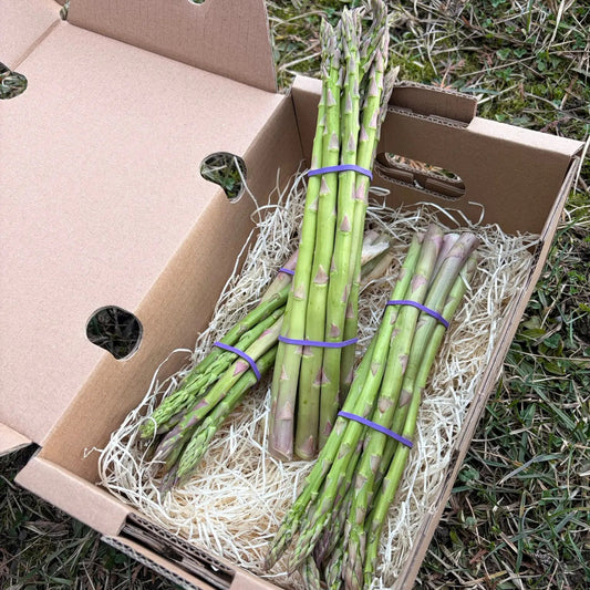 Fresh green asparagus bundles in a delivery box with protective straw, premium vegetables by Tropical Fruit Paradise.