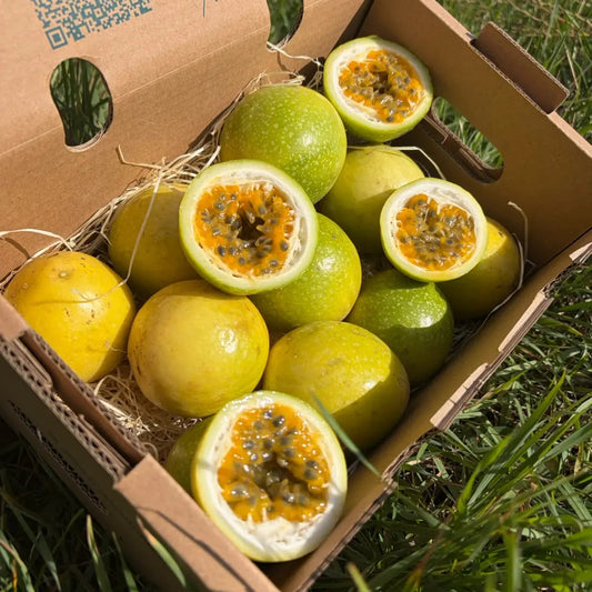 Gold passion fruit (maracuja), yellow-green speckled skin, in a 1 kg Tropical Fruit Paradise box; halves show orange pulp