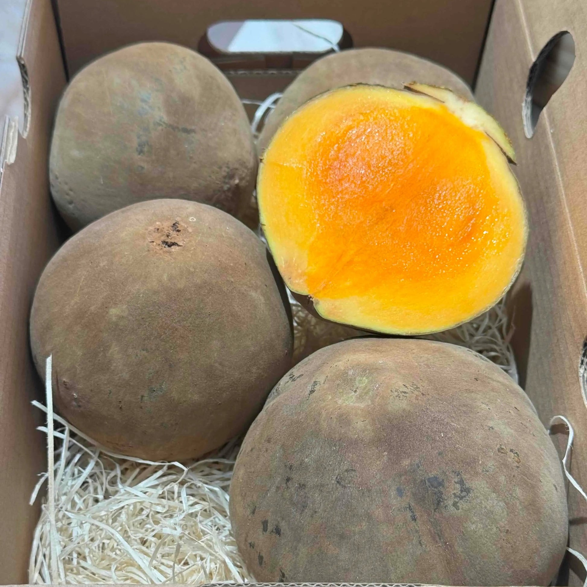 Ripe Mamey Zapote fruit sliced in a Tropical Fruit Paradise branded box, showing creamy orange flesh and exotic texture.