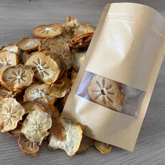Natural dried kaki persimmon slices with a star-shaped pattern and chewy texture, displayed next to an eco-friendly kraft paper pouch on a wooden background.