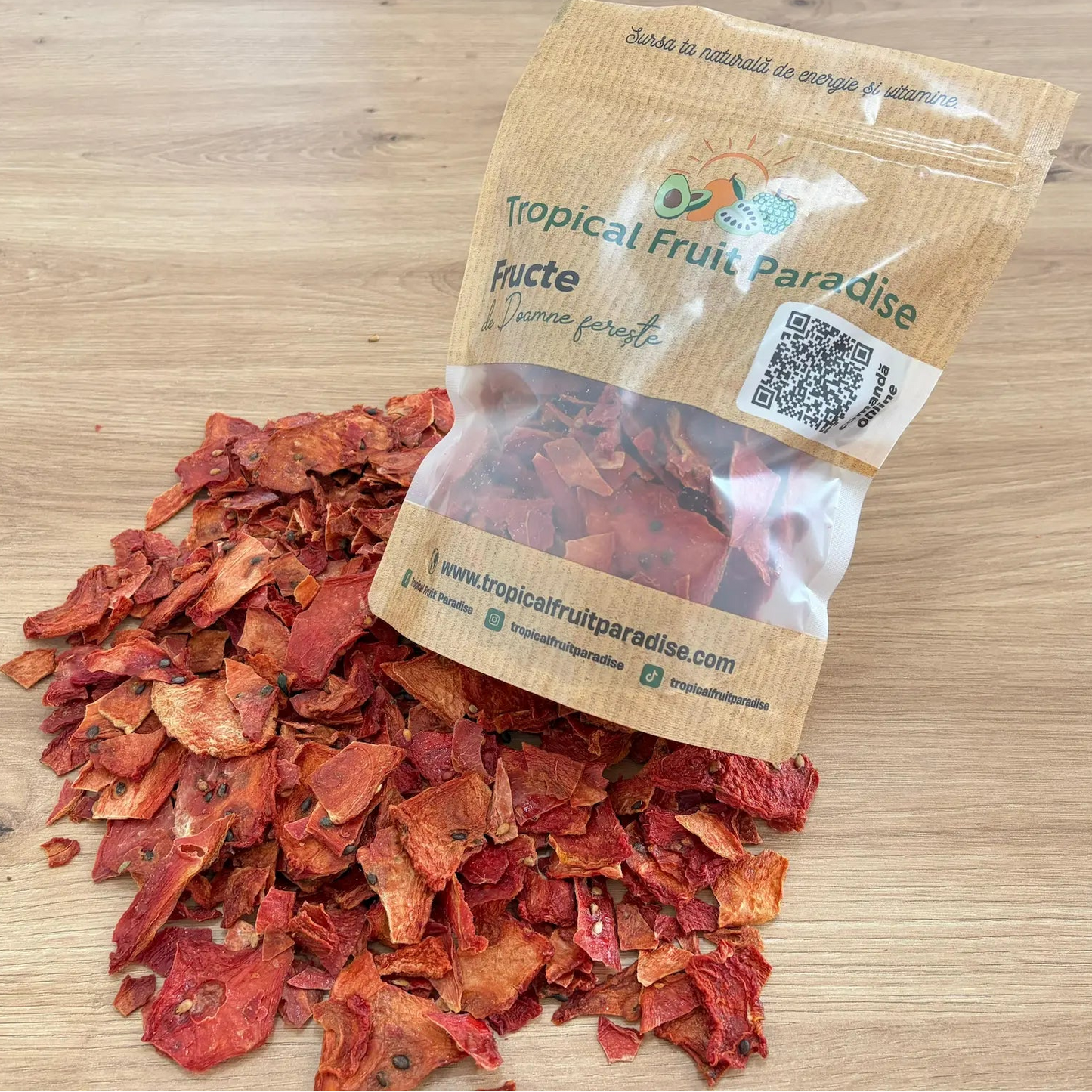 Natural dried watermelon slices with visible black seeds, spilled from a branded Tropical Fruit Paradise kraft pouch, displayed on a light wooden background.